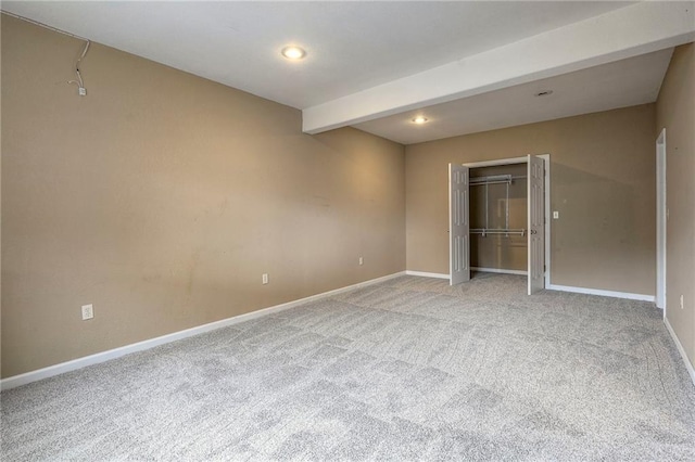 unfurnished bedroom with a closet, light colored carpet, beamed ceiling, and baseboards