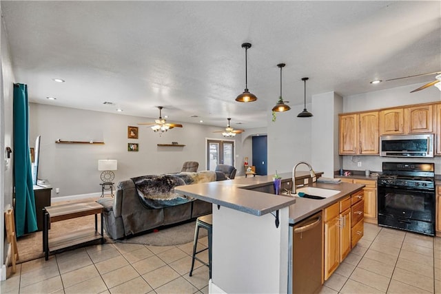 kitchen with pendant lighting, sink, a center island with sink, stainless steel appliances, and a kitchen bar