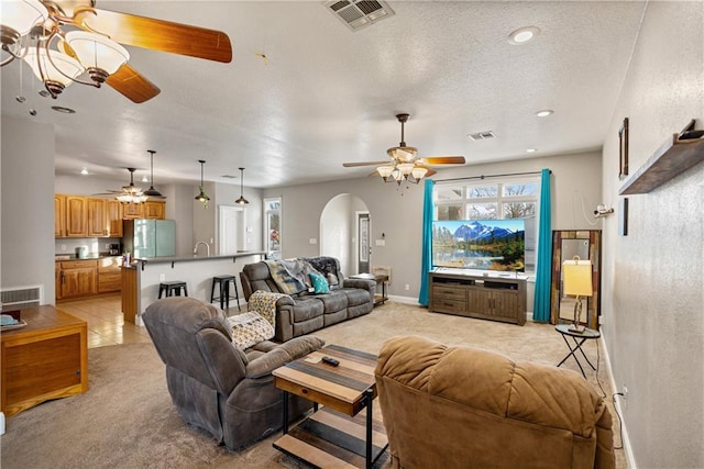 carpeted living room featuring a textured ceiling and ceiling fan