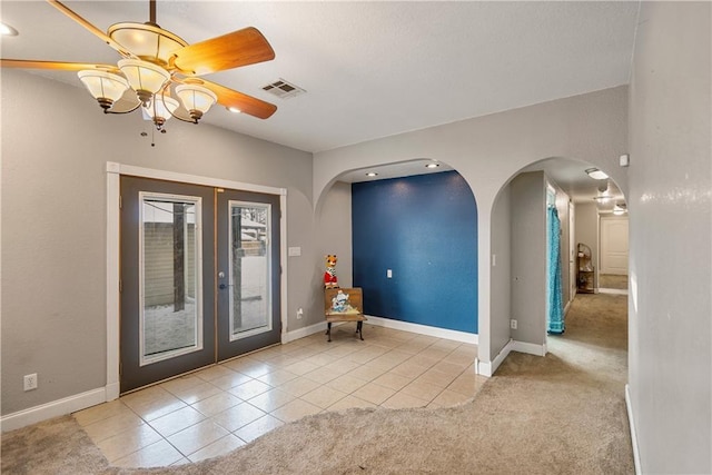 foyer featuring french doors, light colored carpet, and ceiling fan