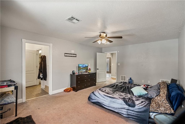 bedroom with ceiling fan, light colored carpet, and a textured ceiling