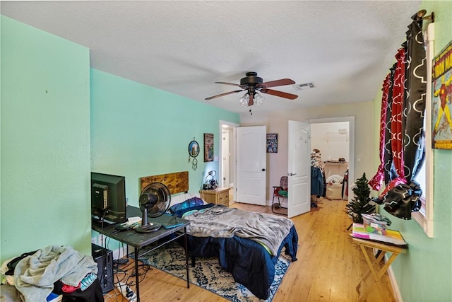 bedroom featuring ceiling fan, a textured ceiling, and light wood-type flooring