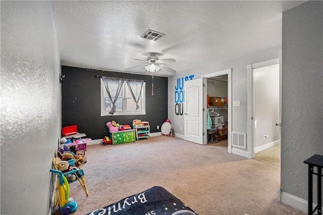 recreation room featuring ceiling fan, carpet floors, and a textured ceiling