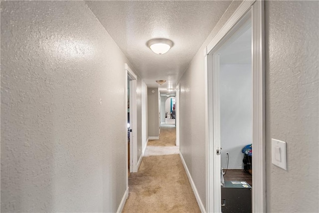 hall with light carpet and a textured ceiling