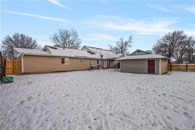 rear view of property featuring central AC unit and an outbuilding