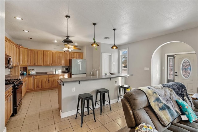 401 N Vine, Caney, KS 67333 - kitchen with a breakfast bar area, arched walkways, stainless steel appliances, light tile patterned floors, and visible vents