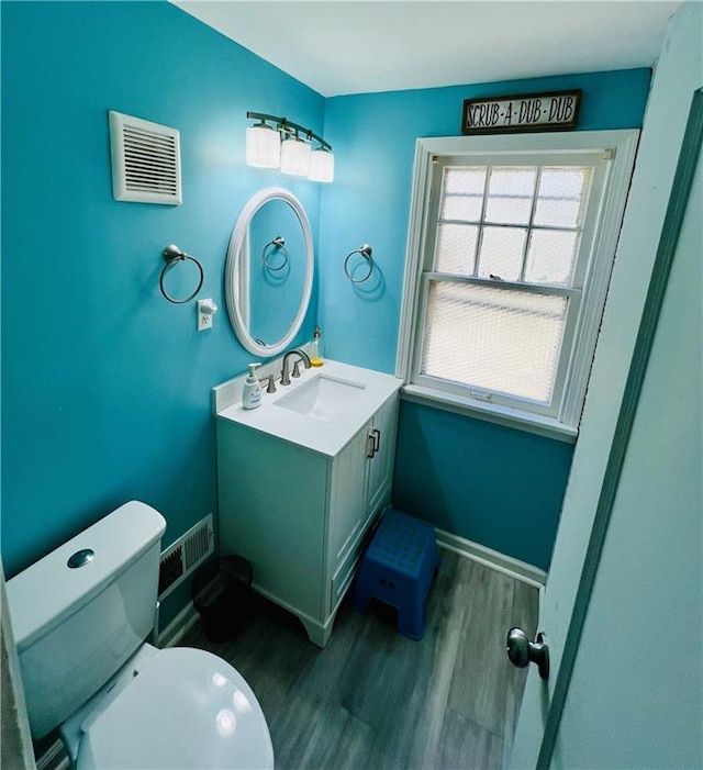 bathroom with vanity, toilet, and hardwood / wood-style floors