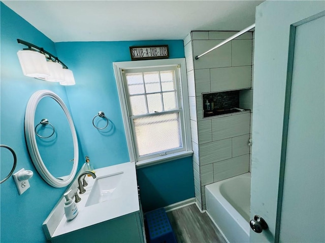 bathroom with hardwood / wood-style flooring, tiled shower / bath, and vanity