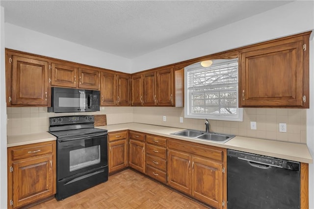 kitchen with sink, decorative backsplash, light parquet floors, black appliances, and a textured ceiling