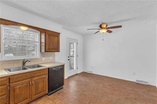 kitchen with sink, tasteful backsplash, a textured ceiling, black dishwasher, and light parquet floors