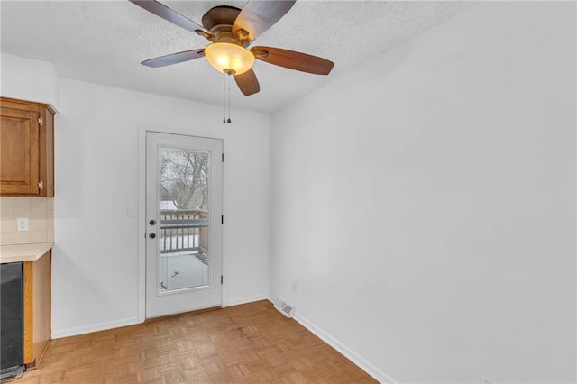 doorway to outside featuring light parquet flooring, ceiling fan, a textured ceiling, and a fireplace