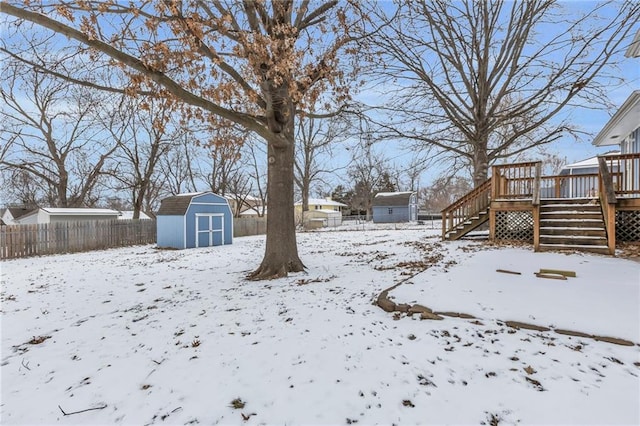 snowy yard with a deck and a shed