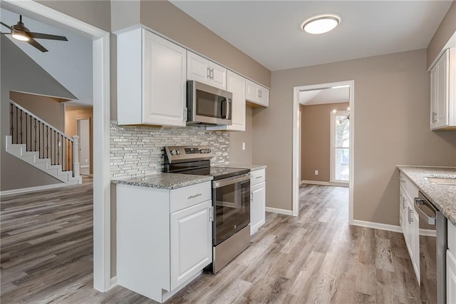 kitchen featuring white cabinetry, appliances with stainless steel finishes, light stone countertops, and tasteful backsplash