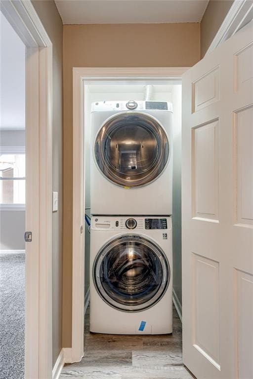 clothes washing area featuring stacked washer and dryer and light wood-type flooring