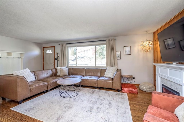 living room with a fireplace, a notable chandelier, wood finished floors, and a textured ceiling