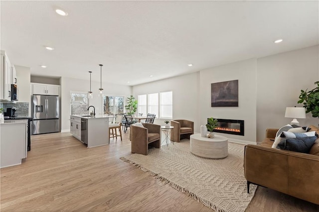 living room featuring sink and light hardwood / wood-style flooring