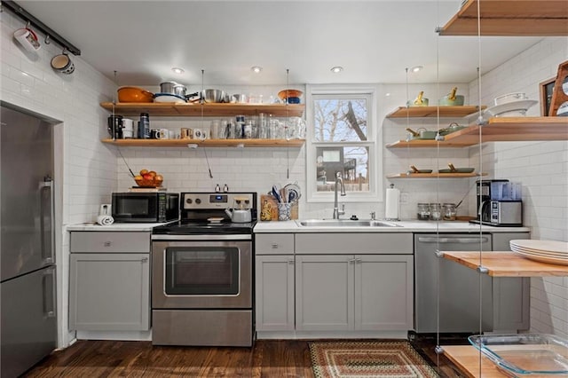 kitchen featuring open shelves, stainless steel appliances, a sink, and gray cabinetry