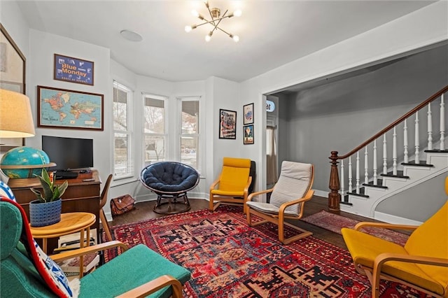 sitting room featuring a chandelier, stairway, and baseboards