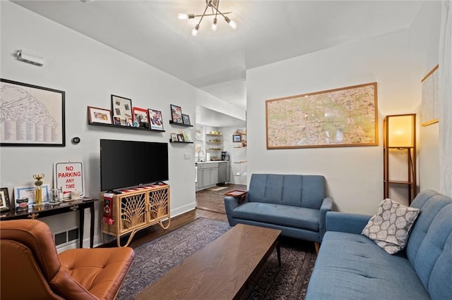 living area with baseboards, an inviting chandelier, and wood finished floors