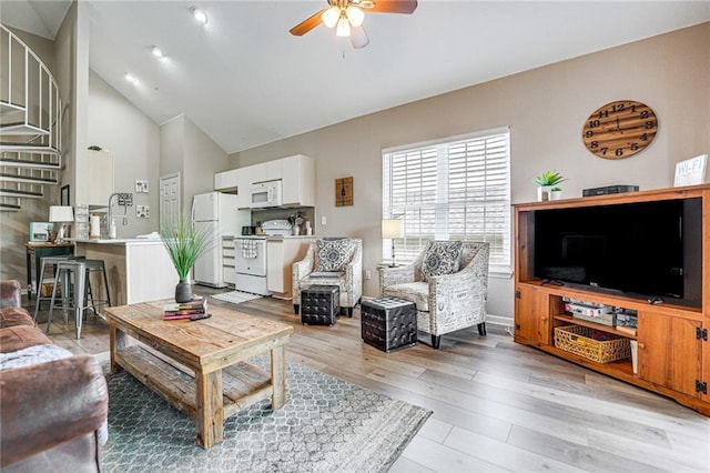 living room with ceiling fan, high vaulted ceiling, and light hardwood / wood-style flooring