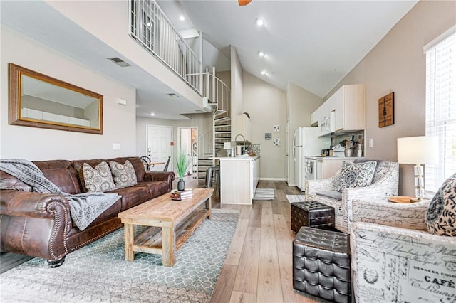 living room featuring high vaulted ceiling and light hardwood / wood-style flooring