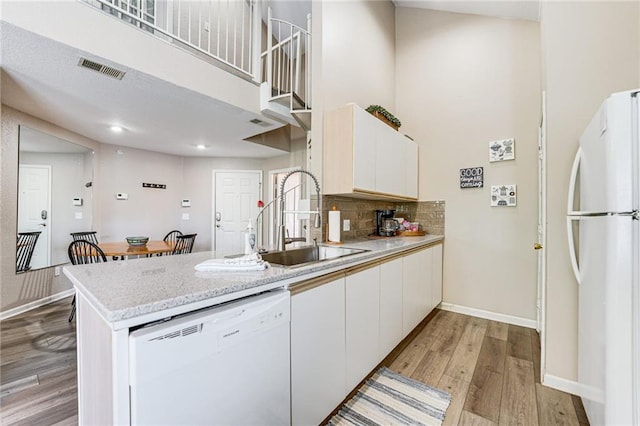 kitchen featuring sink, white cabinets, a high ceiling, light hardwood / wood-style floors, and white appliances