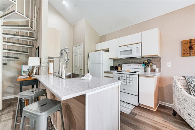 kitchen with sink, white appliances, a breakfast bar, white cabinets, and decorative backsplash