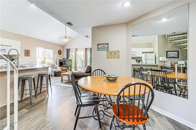 dining room with vaulted ceiling, ceiling fan, and light hardwood / wood-style floors