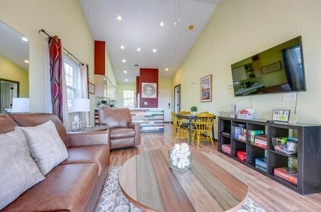 living room featuring high vaulted ceiling and light hardwood / wood-style floors