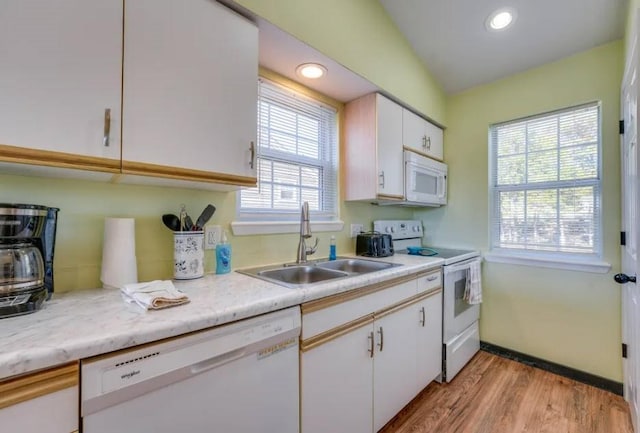 kitchen with lofted ceiling, sink, white appliances, white cabinetry, and light wood-type flooring