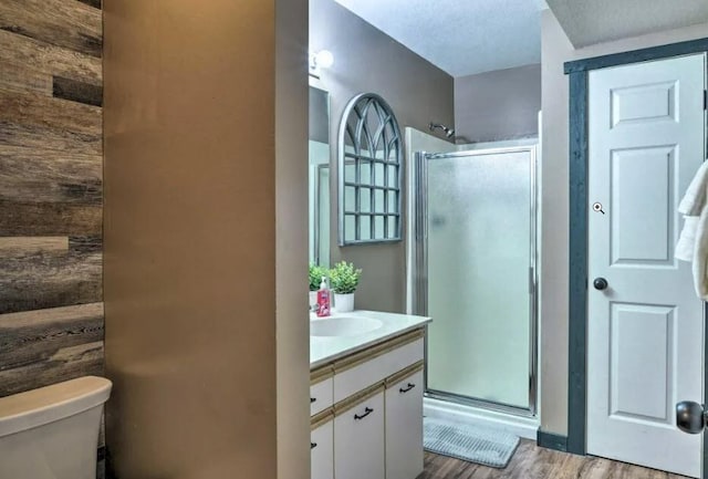 bathroom with an enclosed shower, vanity, hardwood / wood-style floors, and toilet