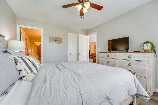 bedroom featuring ceiling fan, ensuite bath, and light wood-type flooring