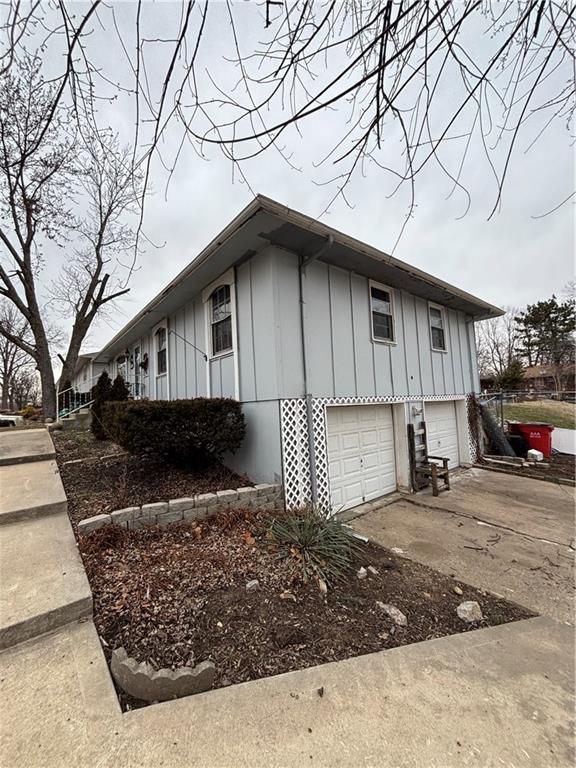 view of property exterior with a garage, board and batten siding, and concrete driveway