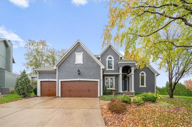 traditional-style home featuring driveway, central air condition unit, a garage, and stucco siding