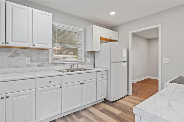 kitchen with sink, light hardwood / wood-style flooring, white refrigerator, decorative backsplash, and white cabinets