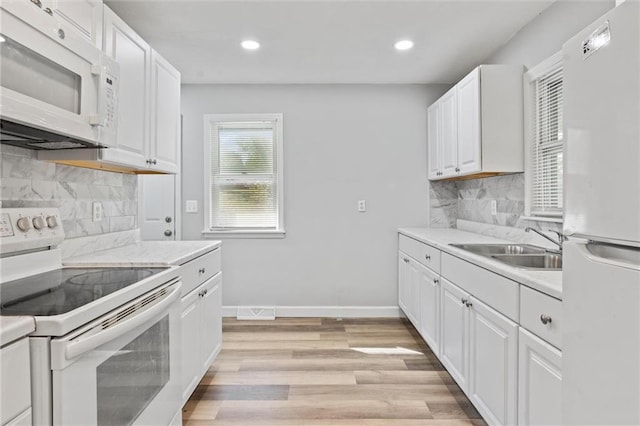 kitchen with sink, white cabinets, decorative backsplash, white appliances, and light wood-type flooring