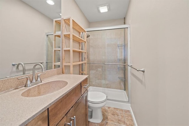 bathroom with vanity, a shower stall, toilet, and baseboards