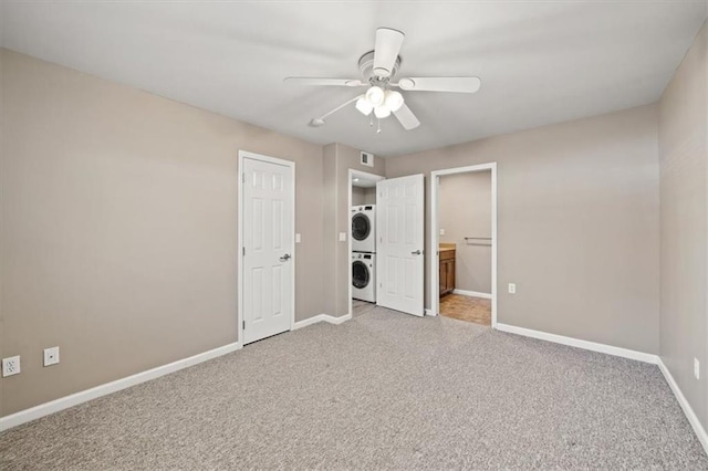 unfurnished bedroom with ensuite bathroom, light colored carpet, visible vents, baseboards, and stacked washer / drying machine