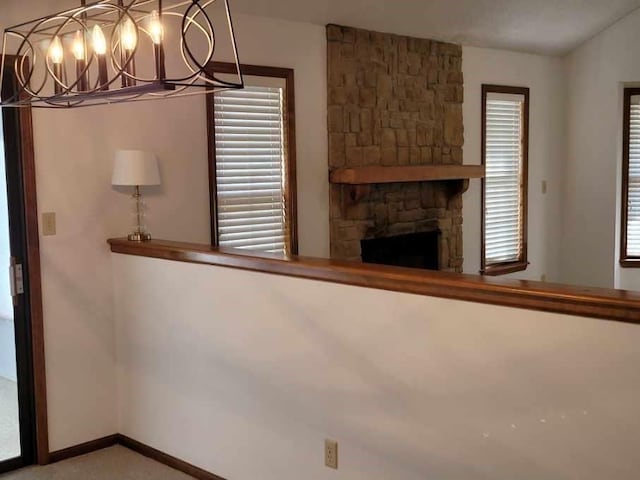 unfurnished living room featuring vaulted ceiling, a stone fireplace, and a chandelier