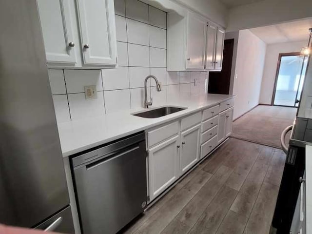 kitchen with sink, tasteful backsplash, wood-type flooring, appliances with stainless steel finishes, and white cabinets