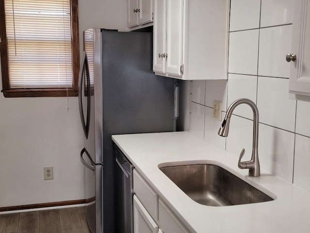 kitchen with white cabinetry, appliances with stainless steel finishes, sink, and backsplash