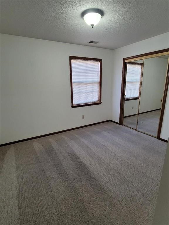 unfurnished bedroom with light carpet, a closet, and a textured ceiling