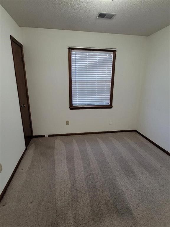 carpeted empty room with a textured ceiling