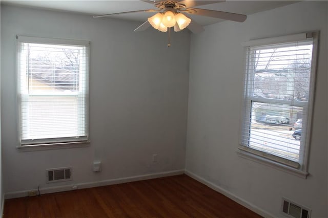 unfurnished room with dark wood-type flooring, visible vents, ceiling fan, and baseboards