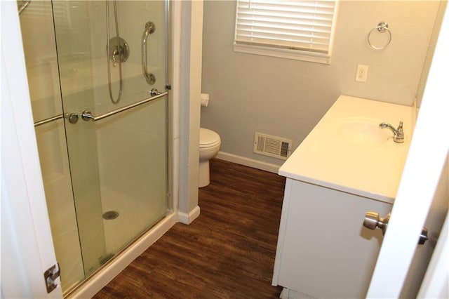 bathroom with a stall shower, baseboards, visible vents, toilet, and wood finished floors