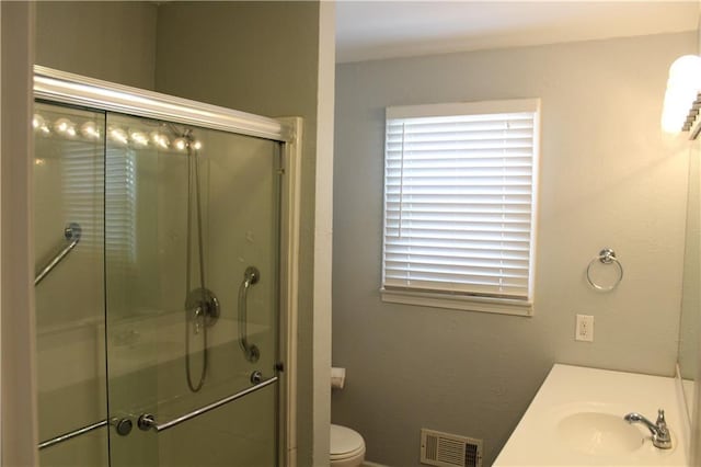 full bathroom with a stall shower, visible vents, vanity, and toilet