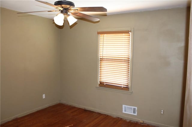 empty room featuring a ceiling fan, baseboards, visible vents, and dark wood-style flooring