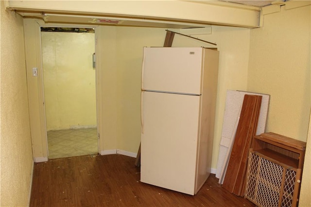 kitchen featuring baseboards, dark wood-style flooring, and freestanding refrigerator