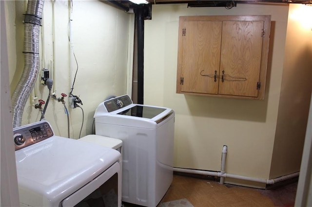 clothes washing area featuring washing machine and clothes dryer and cabinet space