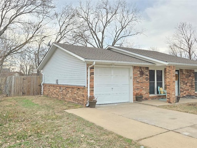 view of side of property featuring a garage, fence, concrete driveway, and brick siding